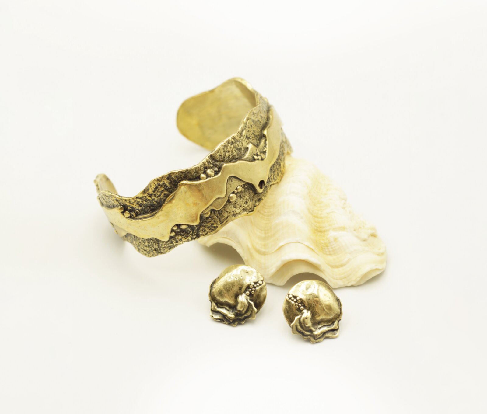 Bronze wave cuff bracelet with matching earrings on a seashell